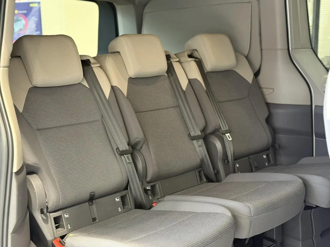 Vue intérieure côté droit des trois sièges arrière gris foncé du Volkswagen California T7 2024 avec ceintures intégrées.