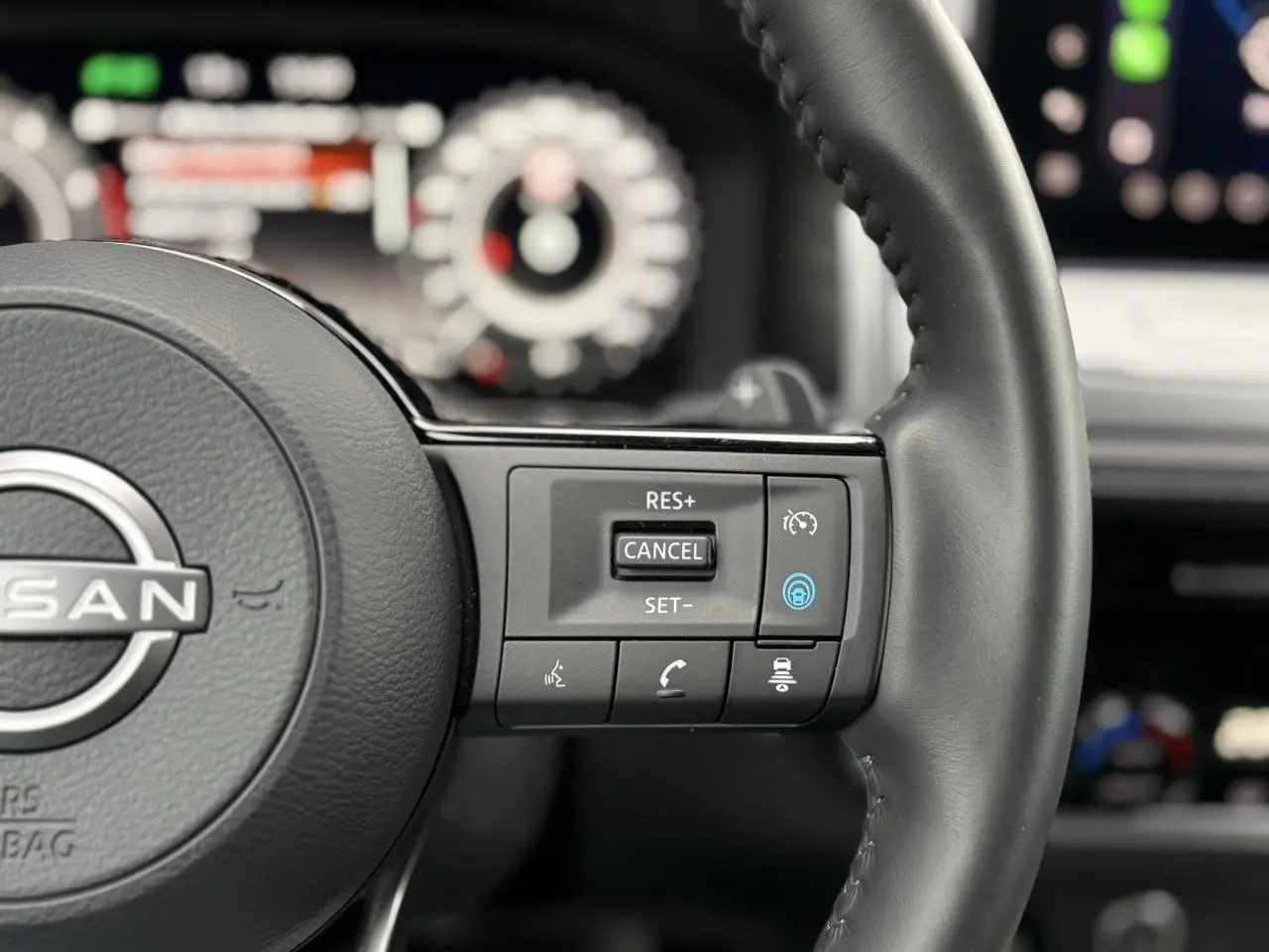 Gros plan sur le volant cuir du Nissan Qashqai 2024, avec commandes de régulateur de vitesse et assistance au maintien de voie.