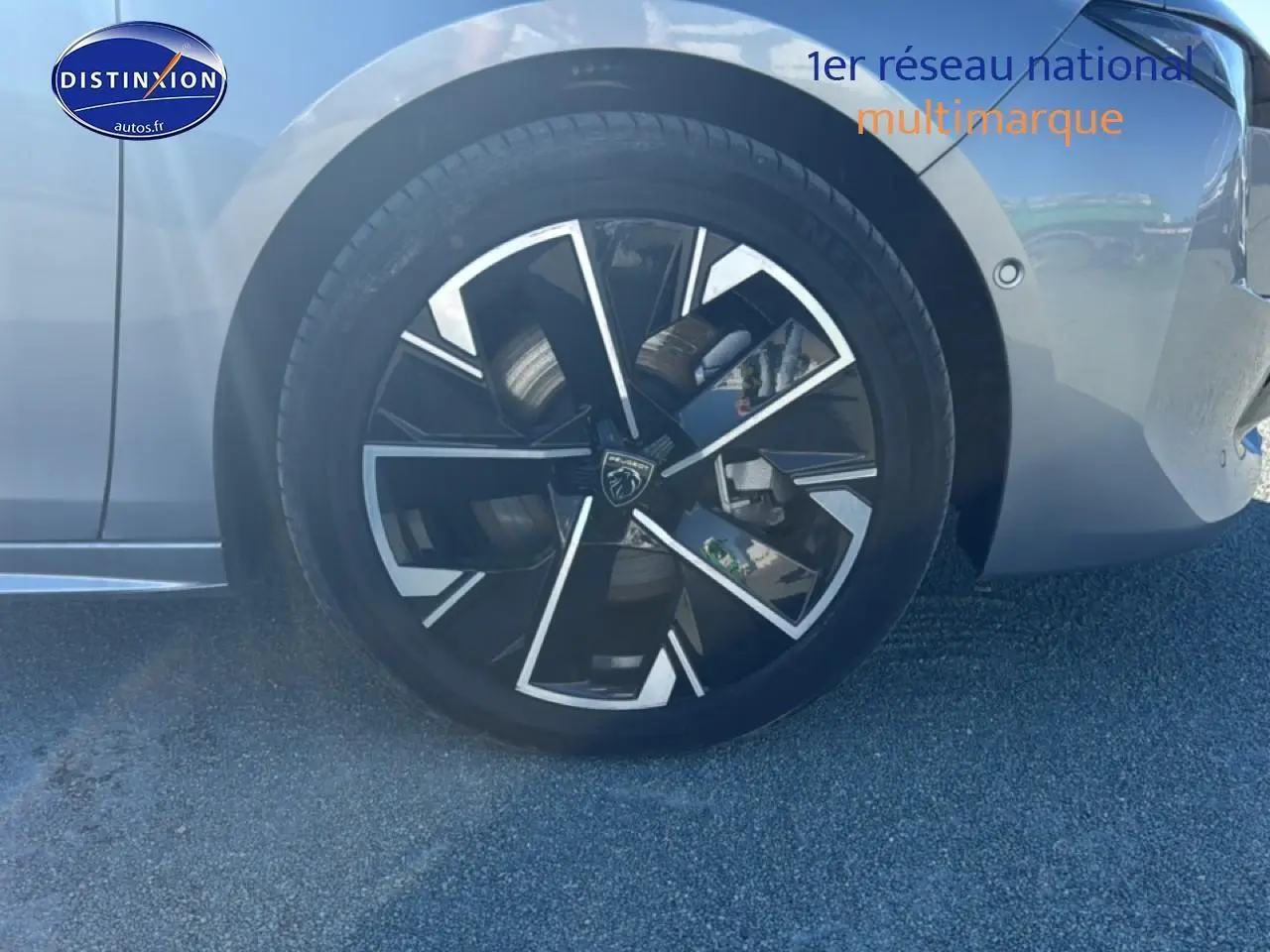 Gros plan sur la roue avant droite avec jante alu noire et argentée d'une Peugeot 508 SW gris artense.