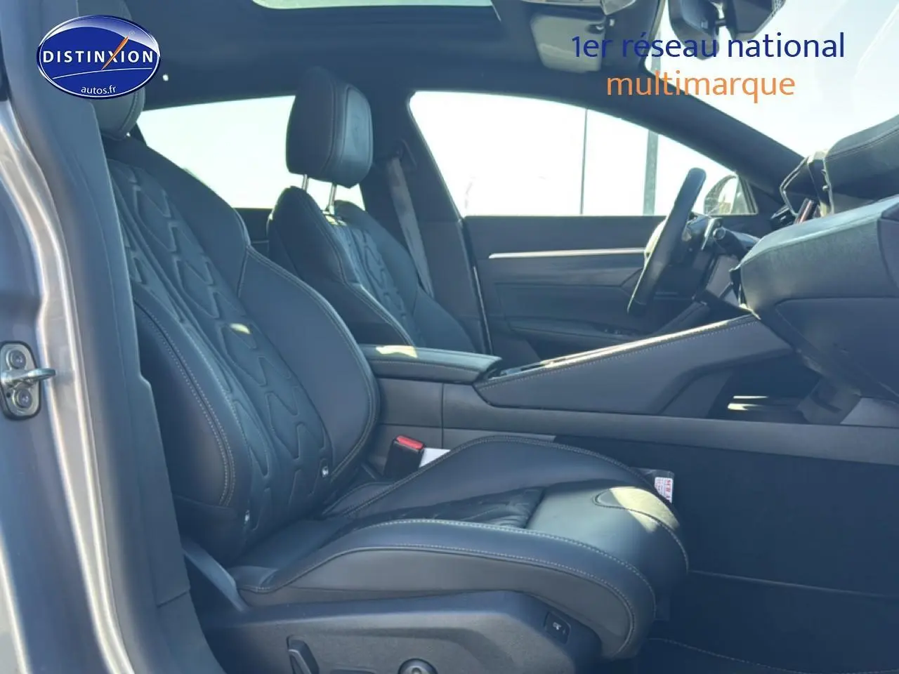 Vue intérieure côté gauche montrant les sièges avant en cuir noir et l'accoudoir central d'une Peugeot 508 SW gris artense.