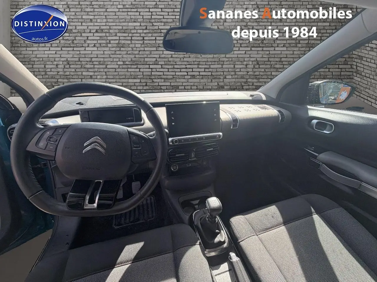 Vue intérieure avant de la Citroën C4 Cactus 2020, volant cuir, levier manuel, sellerie tissu gris, tableau de bord moderne.