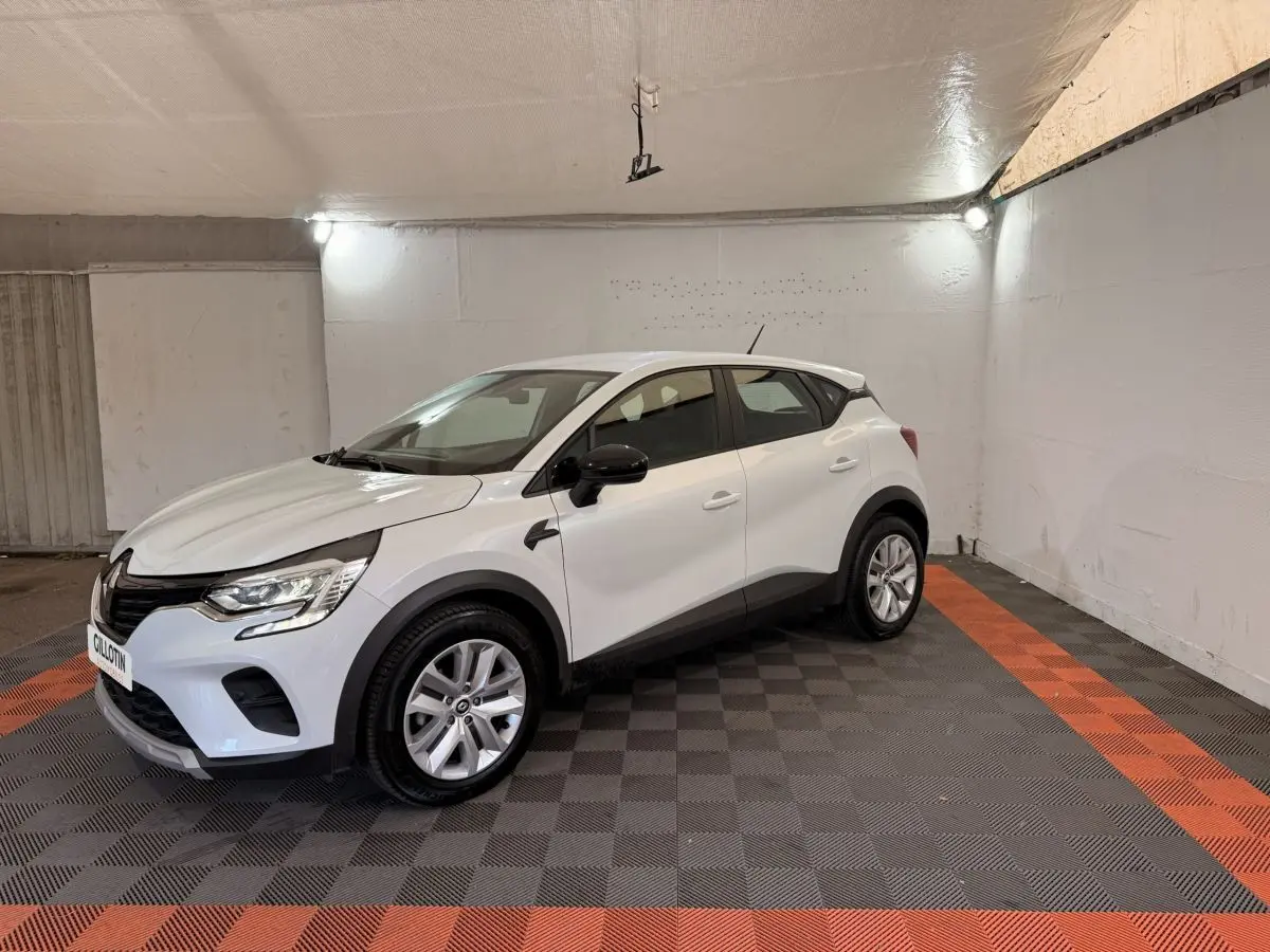 Renault Captur blanc vue 3/4 avant droit dans un garage avec rétroviseurs noirs et jantes argentées.