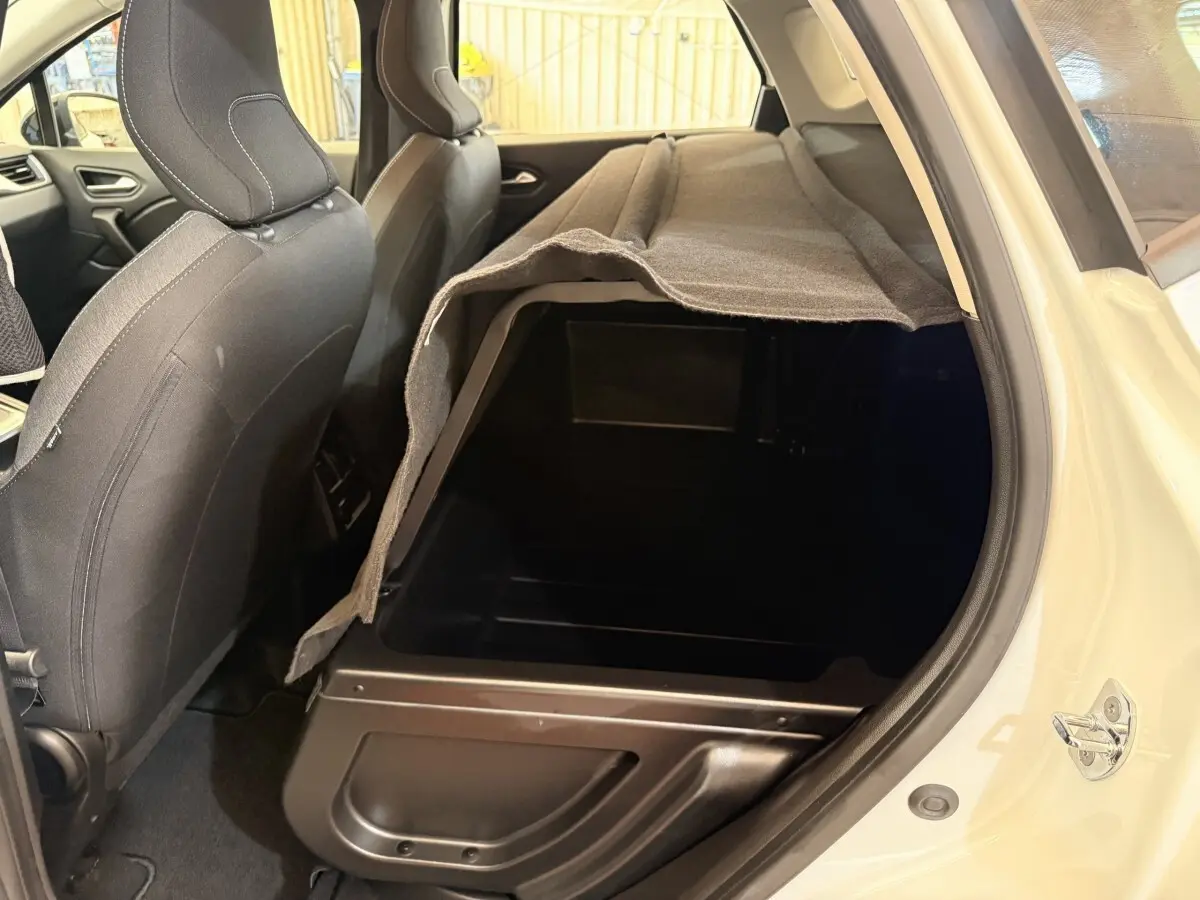 Vue intérieure côté arrière droit du coffre modulable du Renault Captur blanc, montrant le rangement sous plancher.