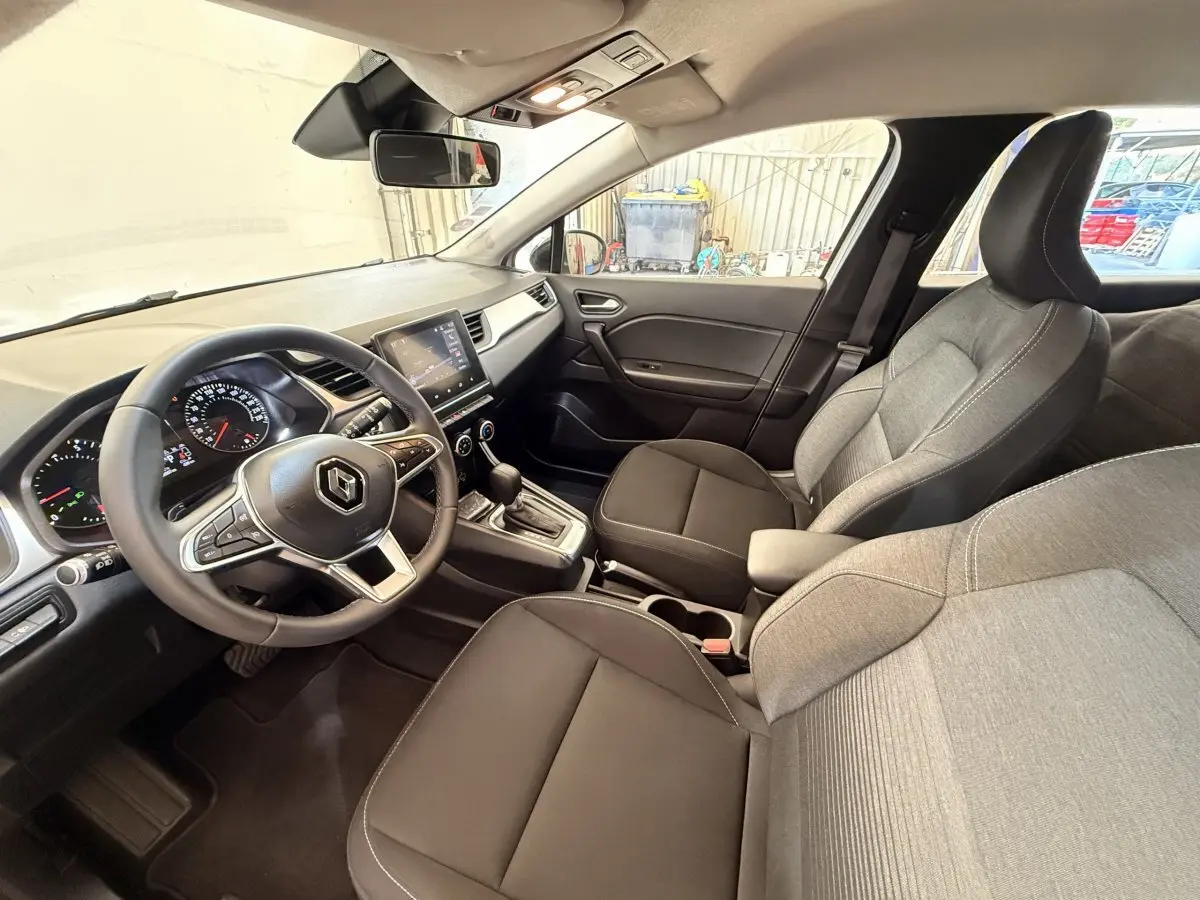 Vue intérieure côté conducteur du Renault Captur Business 2021, sièges tissu gris et noir, tableau de bord avec écran tactile.