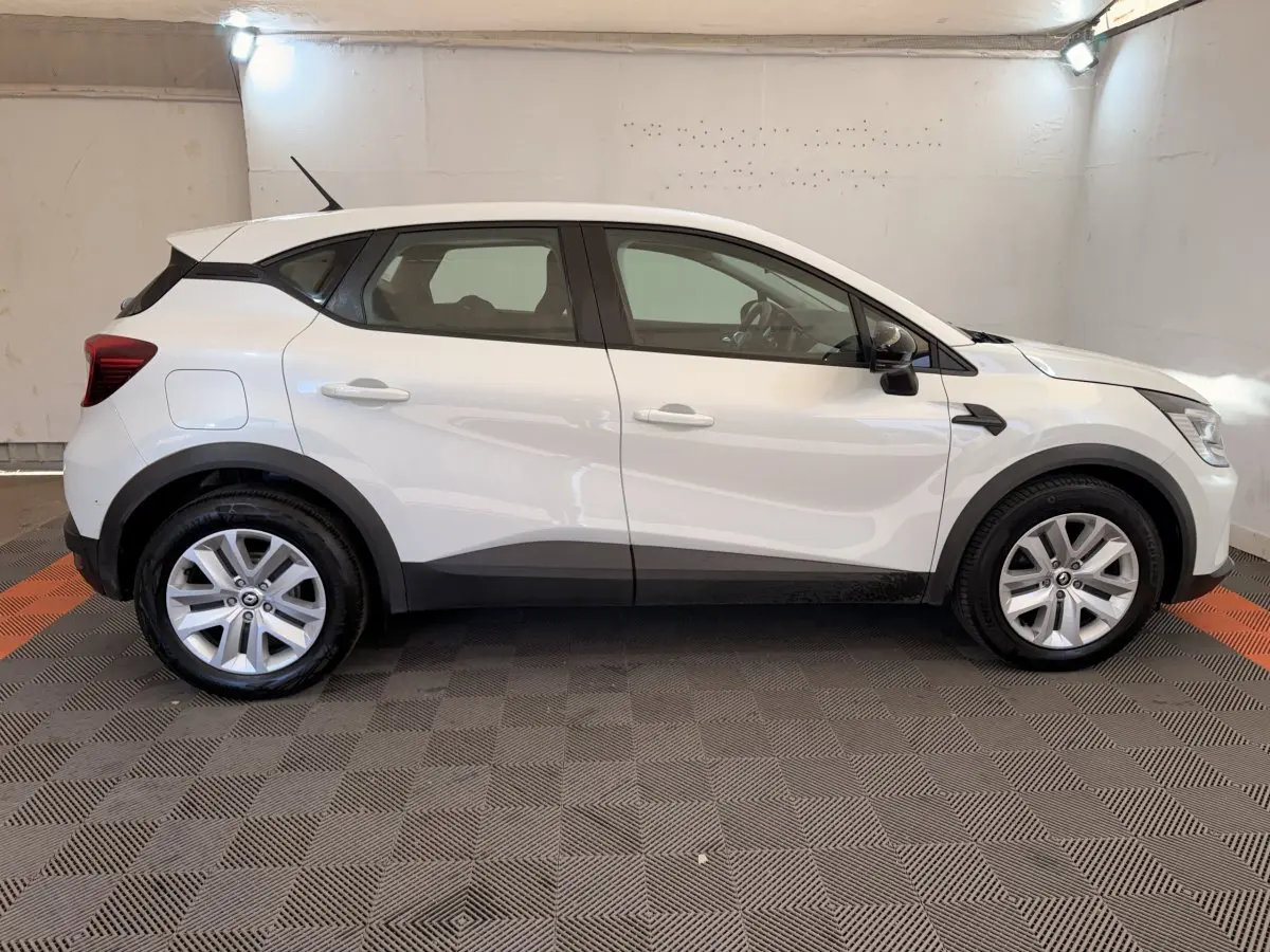 Profil côté gauche d'un Renault Captur Business blanc, avec jantes alliage et protections noires sur bas de caisse.