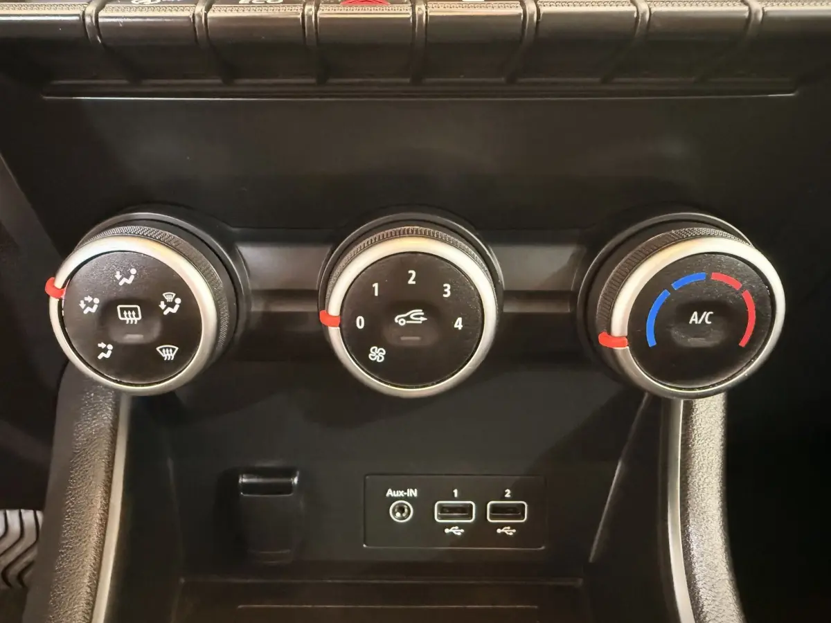 Gros plan sur les commandes de climatisation et les ports USB du tableau de bord noir du Renault Captur blanc 2021.