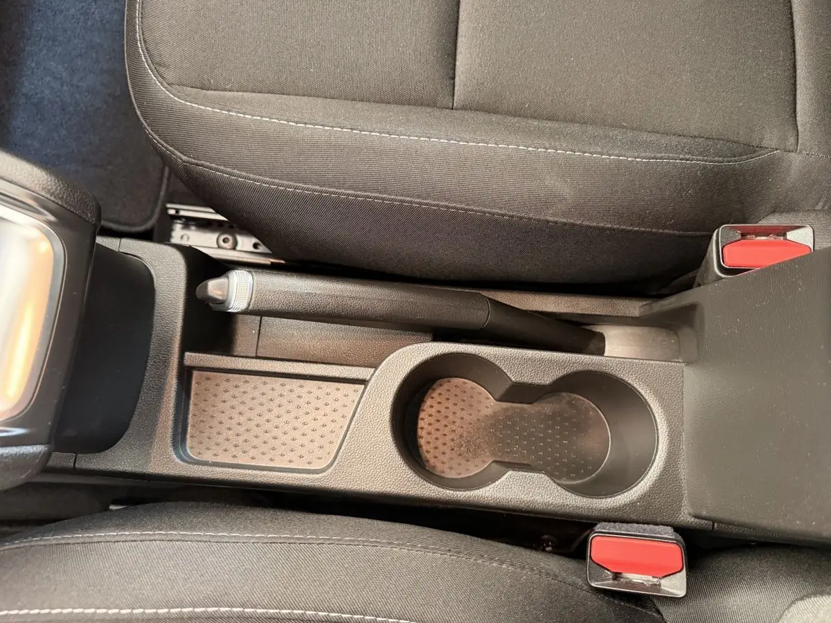 Vue plongeante sur la console centrale noire du Renault Captur 2021 avec frein à main manuel et porte-gobelets.