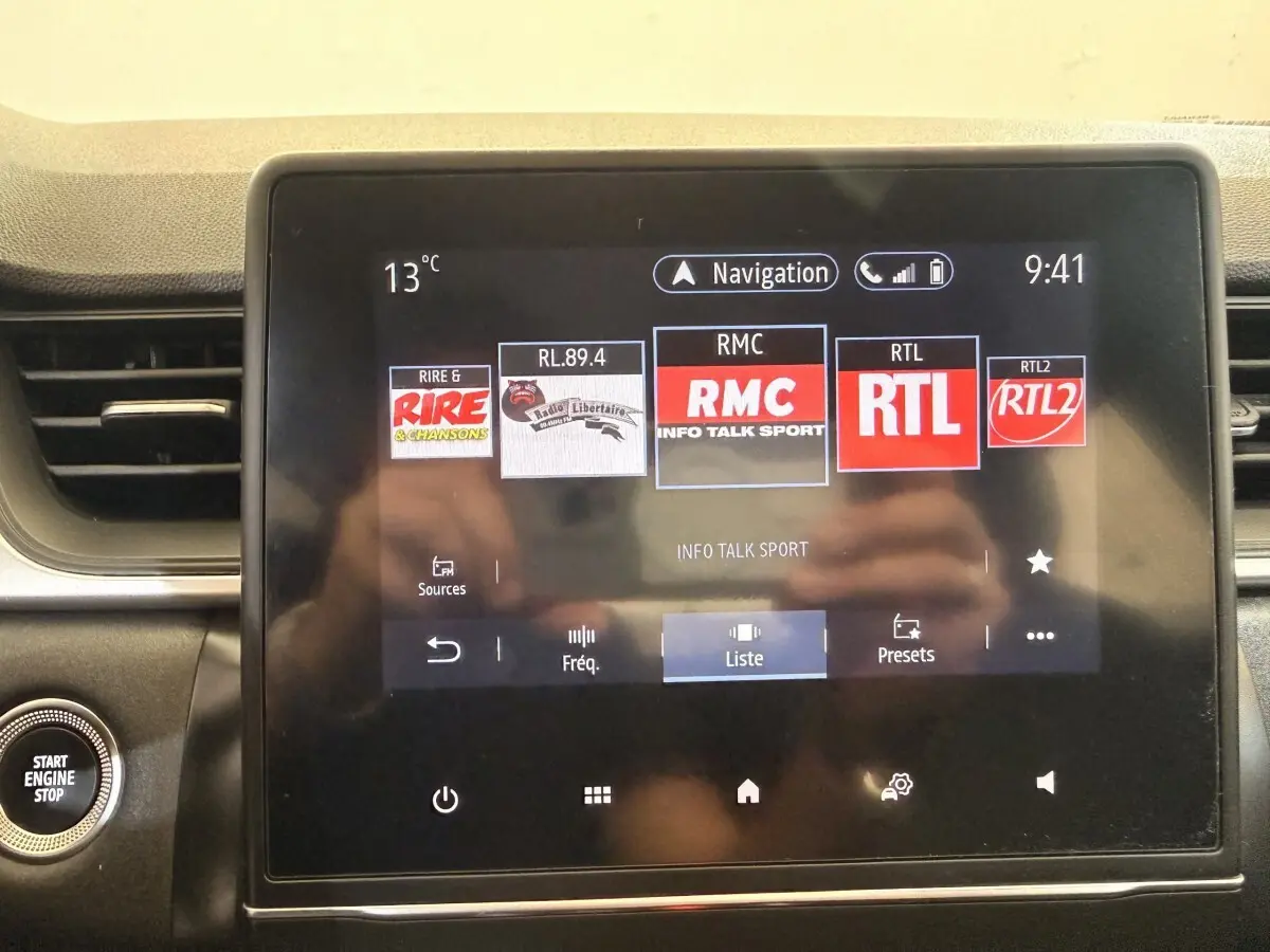 Écran tactile central du tableau de bord du Renault Captur Business blanc, affichant les radios et la navigation.