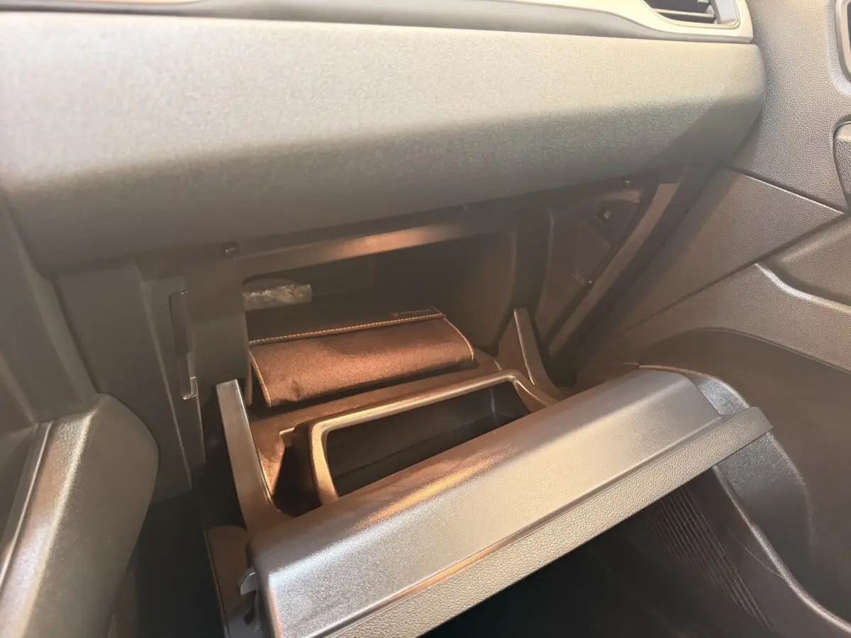 Vue intérieure du coffre à gants ouvert côté passager du Renault Captur blanc, montrant un rangement avec pochette.
