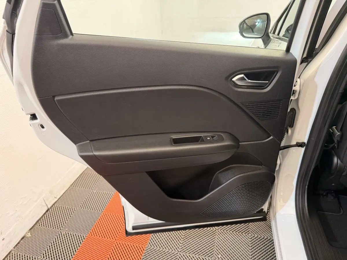 Vue intérieure de la porte arrière droite noire d'un Renault Captur blanc, avec commande de fenêtre et haut-parleur intégré.