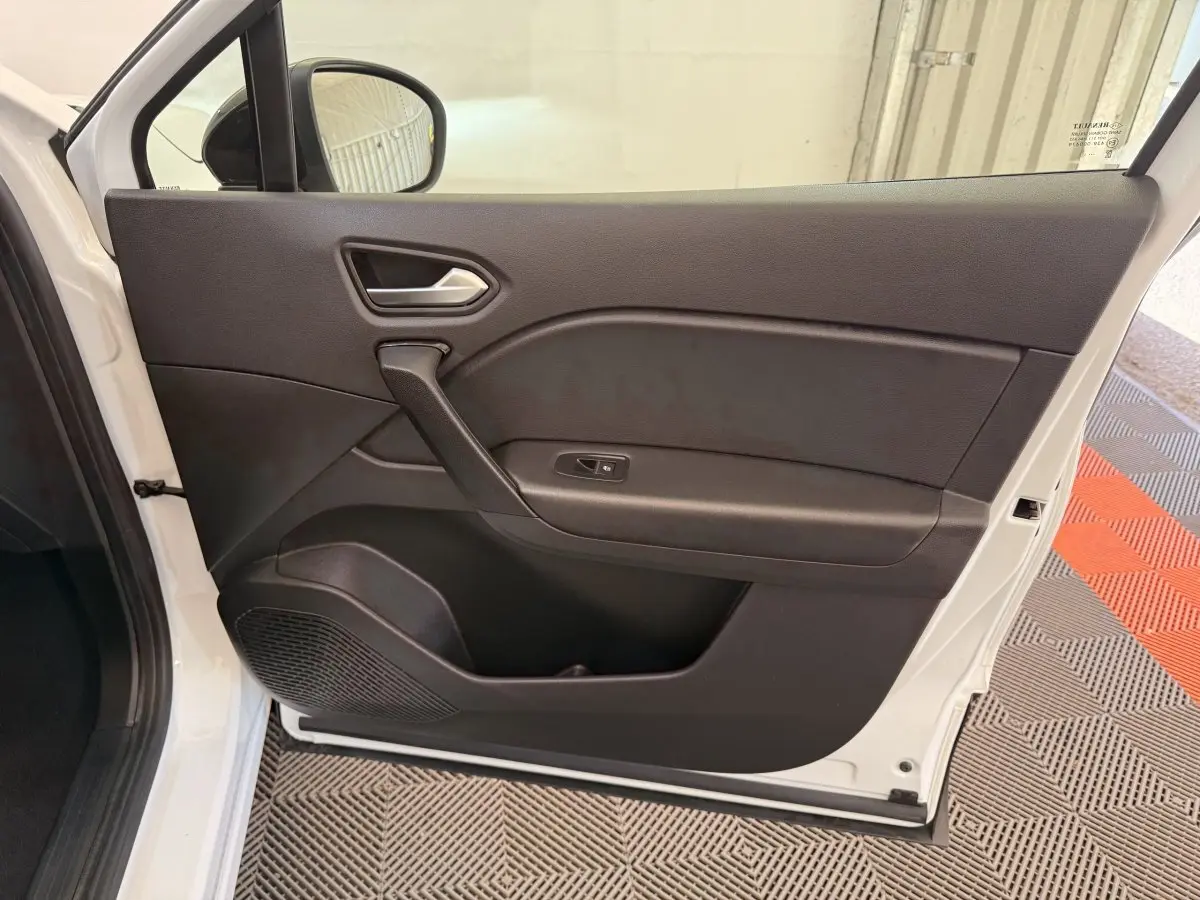 Vue intérieure de la porte avant gauche noire du Renault Captur blanc 2021, avec poignée et commande de vitre visible.