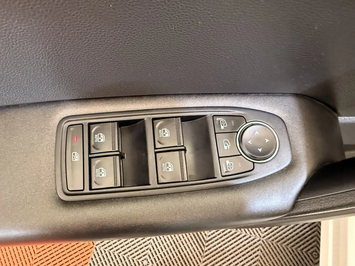 Gros plan sur les commandes de lève-vitres et rétroviseurs sur la porte côté conducteur d’un Renault Captur blanc.