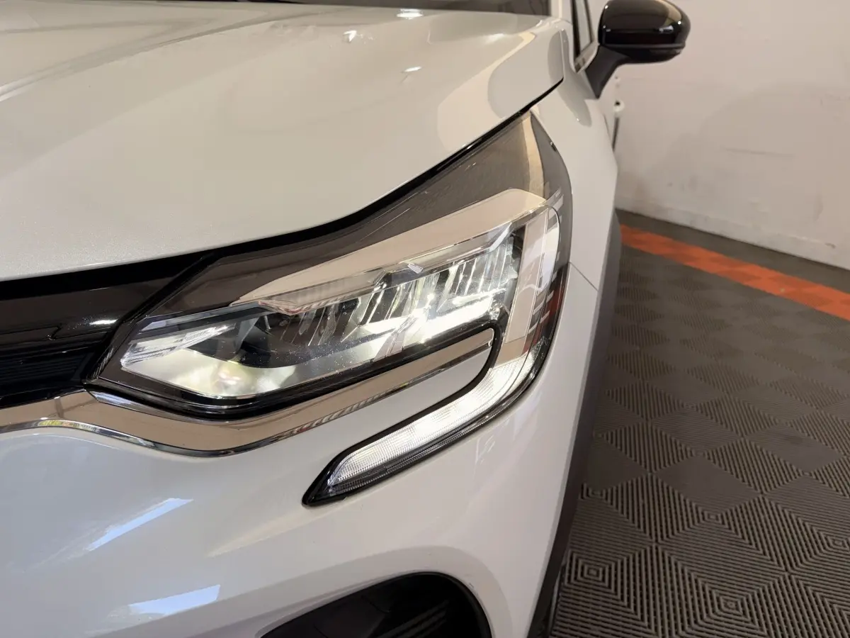 Gros plan sur le phare avant droit blanc du Renault Captur Business TCe 140 EDC FAP 2021 avec rétroviseur noir.