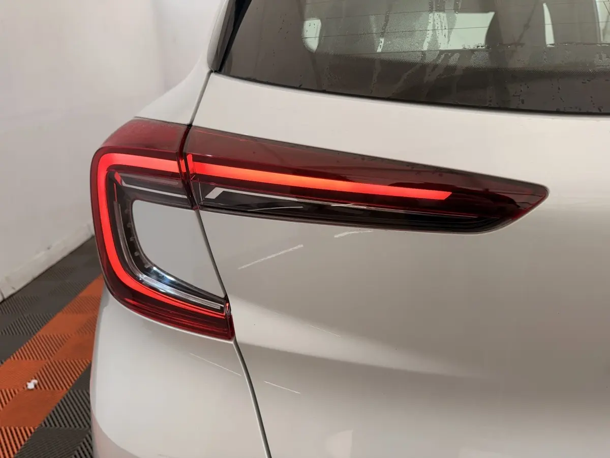 Gros plan sur le feu arrière droit rouge allumé d’un Renault Captur blanc, vue arrière côté droit.