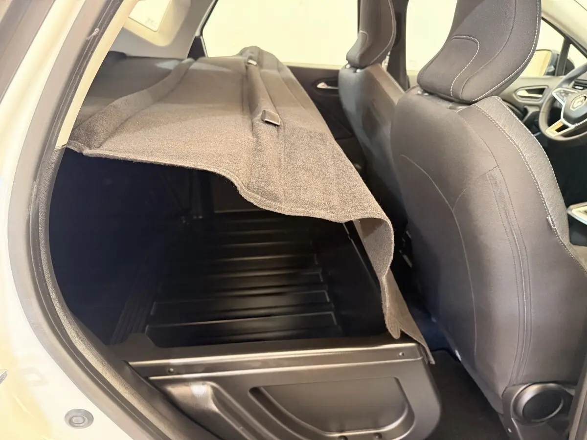 Vue intérieure côté gauche du coffre ouvert du Renault Captur blanc, avec banquette arrière et sièges avant visibles.