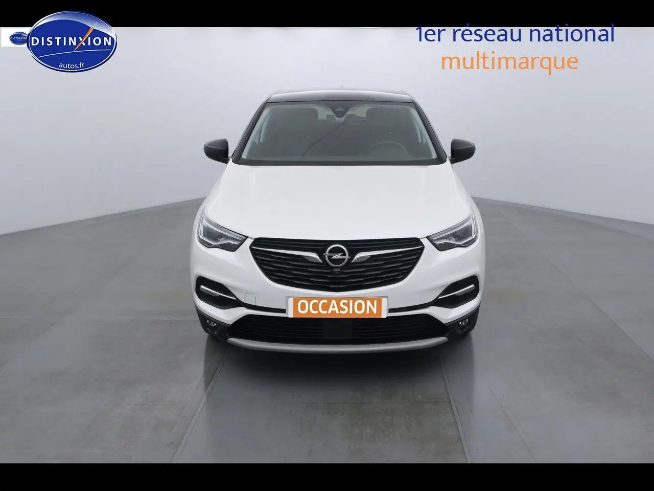 Vue frontale d'un Opel Grandland X blanc nacré avec calandre noire et phares LED dans un studio lumineux.