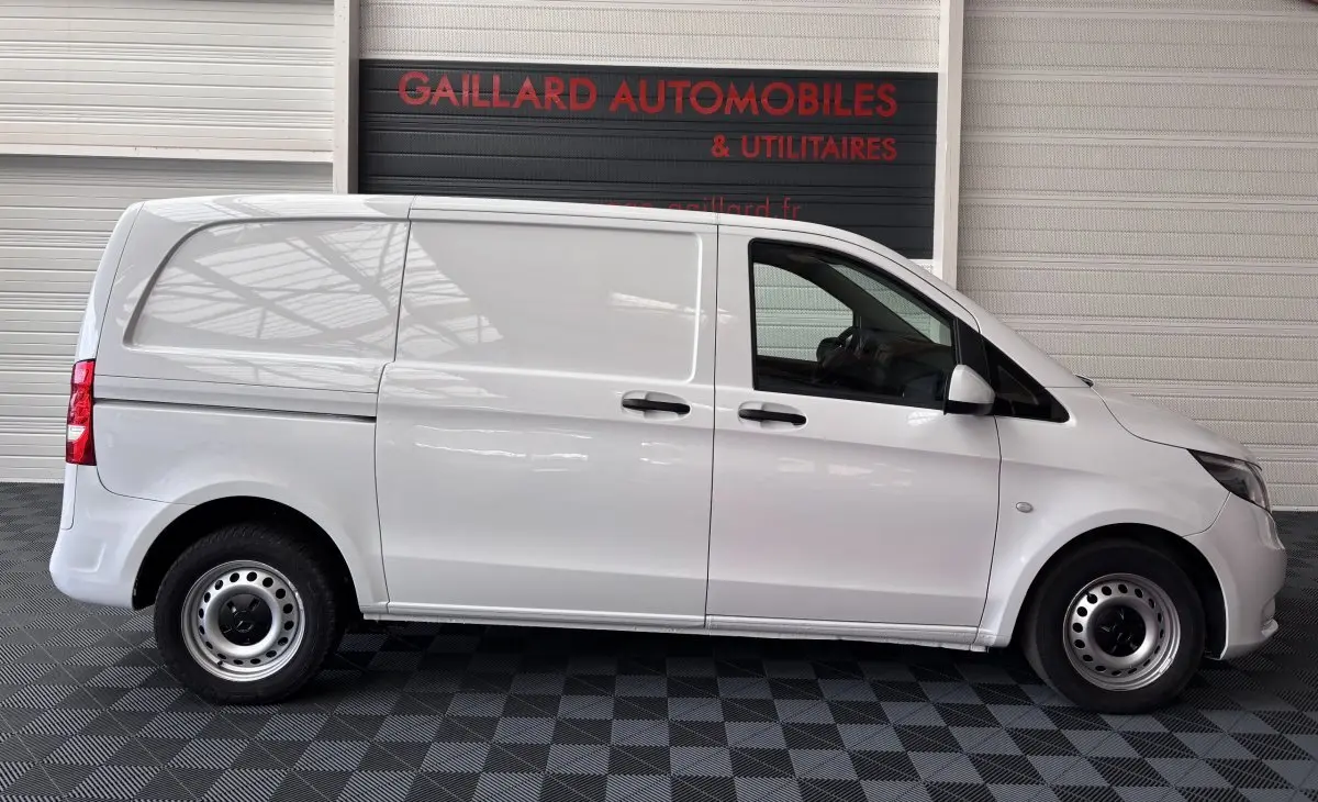 Profil droit d'un utilitaire Mercedes Vito 111 CDI Compact blanc, avec deux portes latérales et hayon arrière fermé.