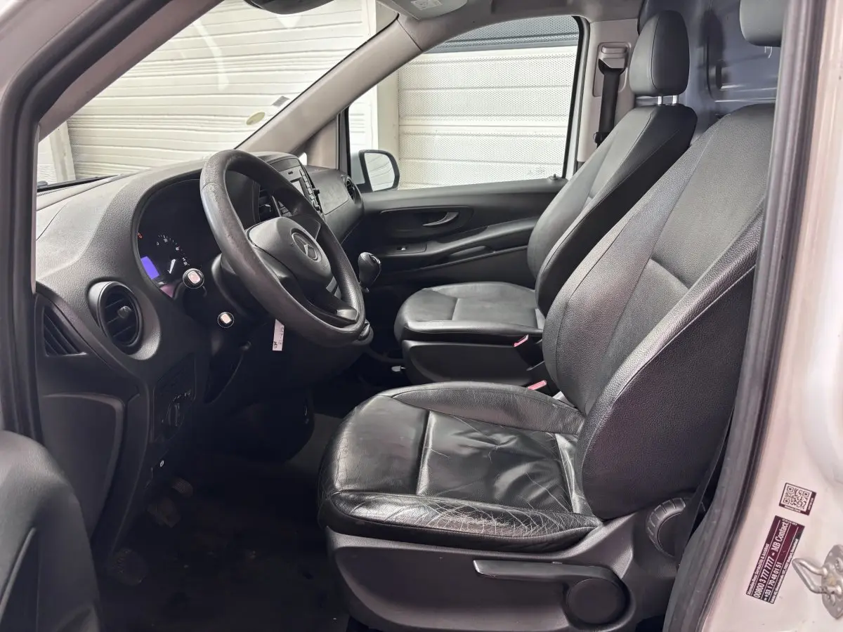 Vue intérieure côté conducteur du Mercedes Vito blanc 2016, sièges en cuir noir et tableau de bord visible.