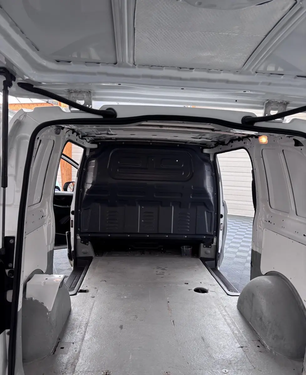 Vue intérieure arrière du Mercedes Vito blanc 111 CDI Compact 2 portes, montrant l’espace de chargement vide et la cloison pleine noire.