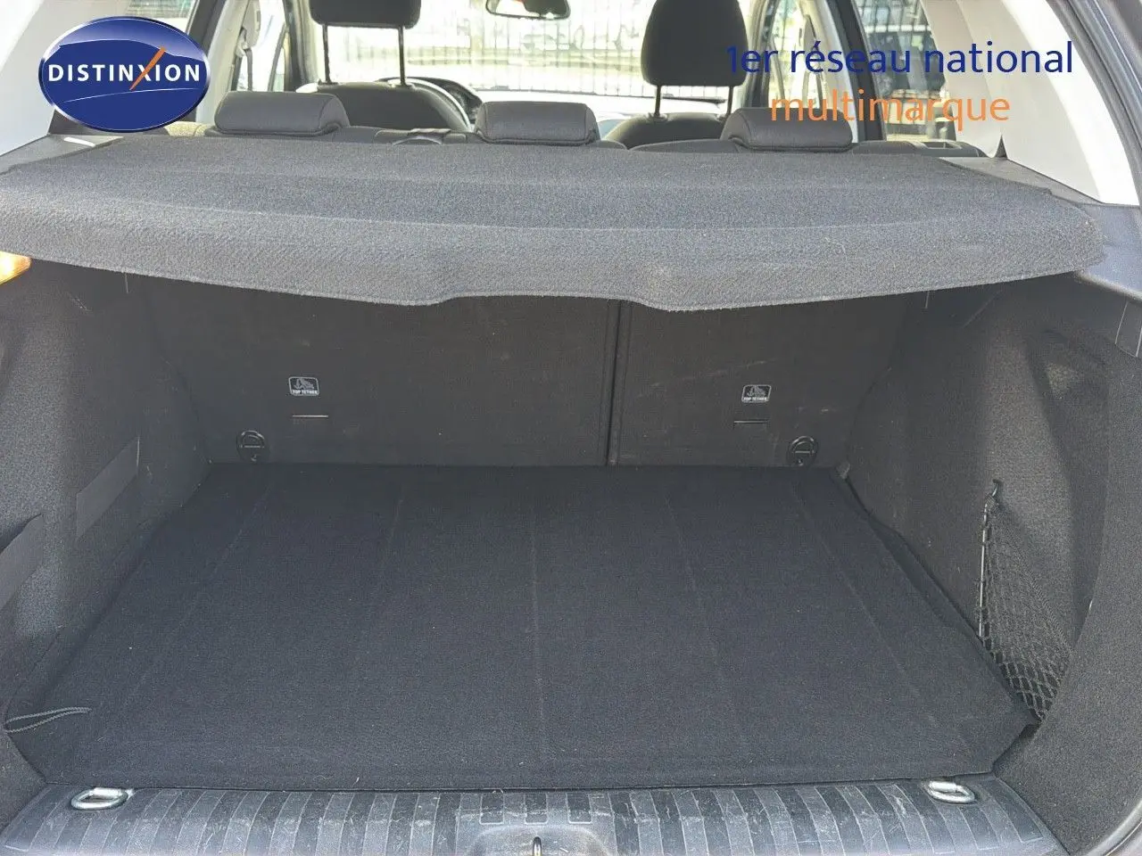 Coffre ouvert d'un Peugeot 2008 gris platinium, vue arrière montrant le tapis de coffre et la plage arrière.