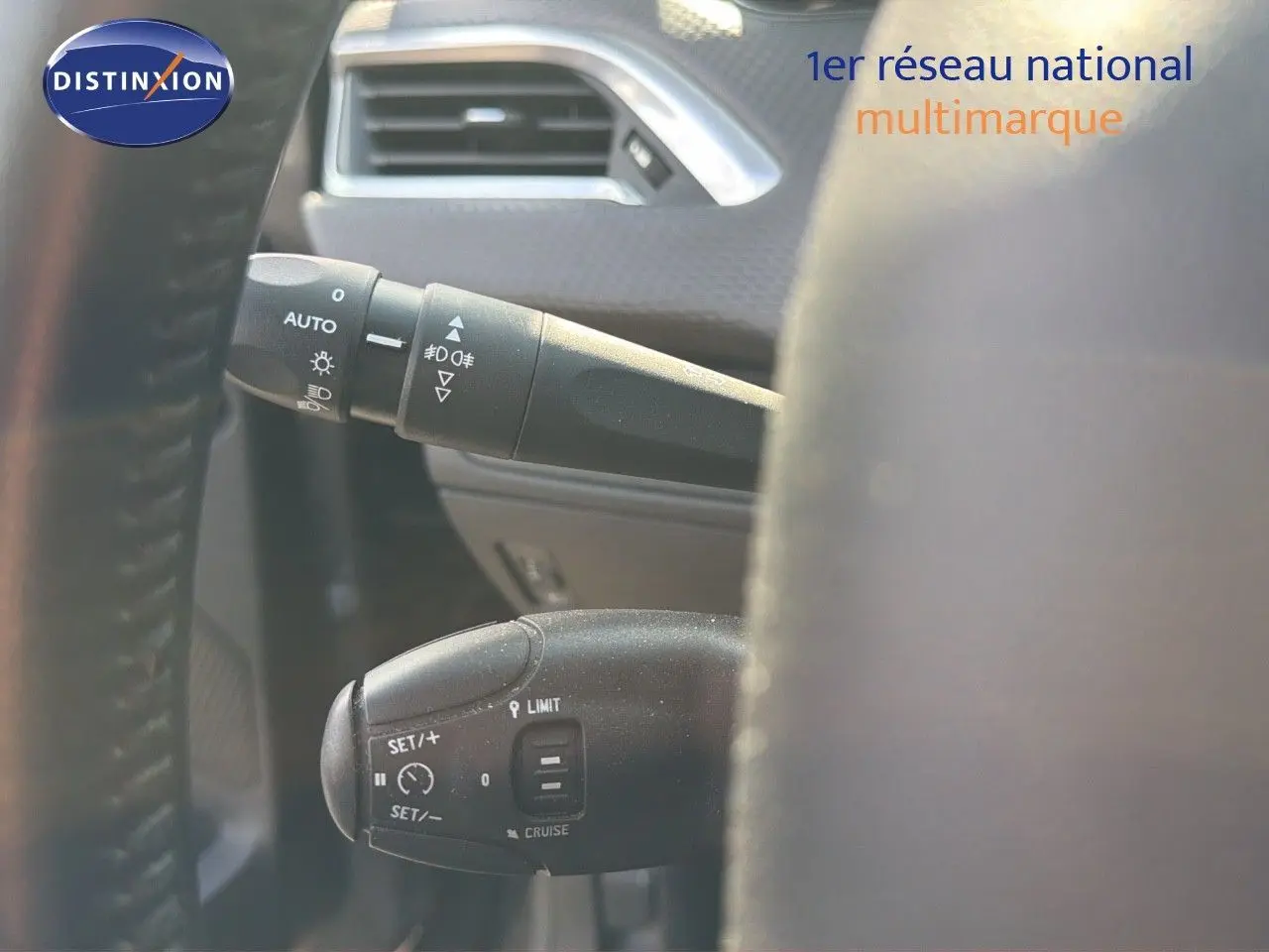 Gros plan sur les commandes au volant du Peugeot 2008 gris platinium, mettant en valeur les fonctions de régulateur et éclairage.