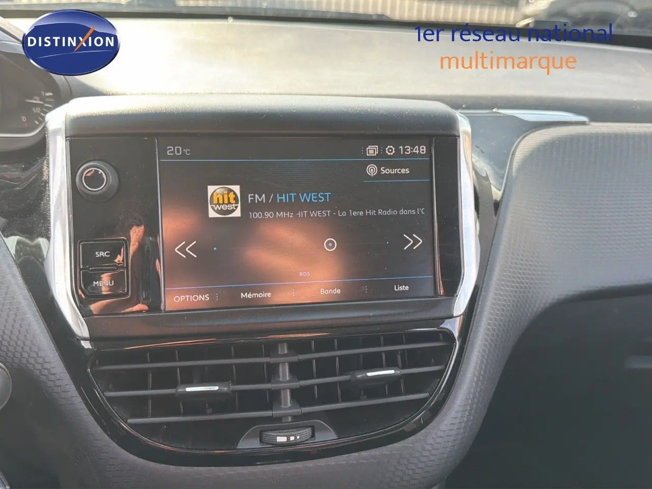 Tableau de bord du Peugeot 2008 gris platinium, vue centrée sur l'écran tactile multimédia affichant une radio FM.