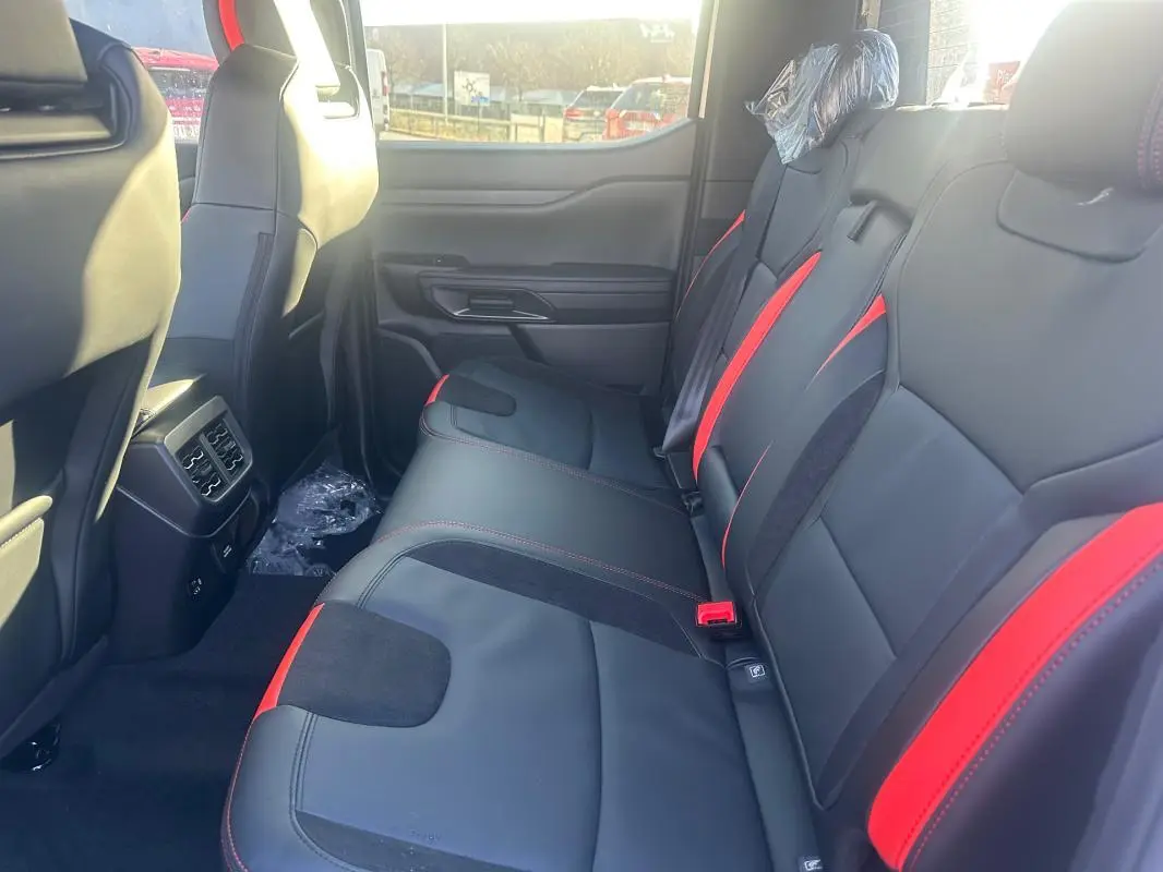 Vue latérale intérieure arrière du Ford Ranger 2025, sièges en cuir noir avec surpiqûres et inserts rouges.