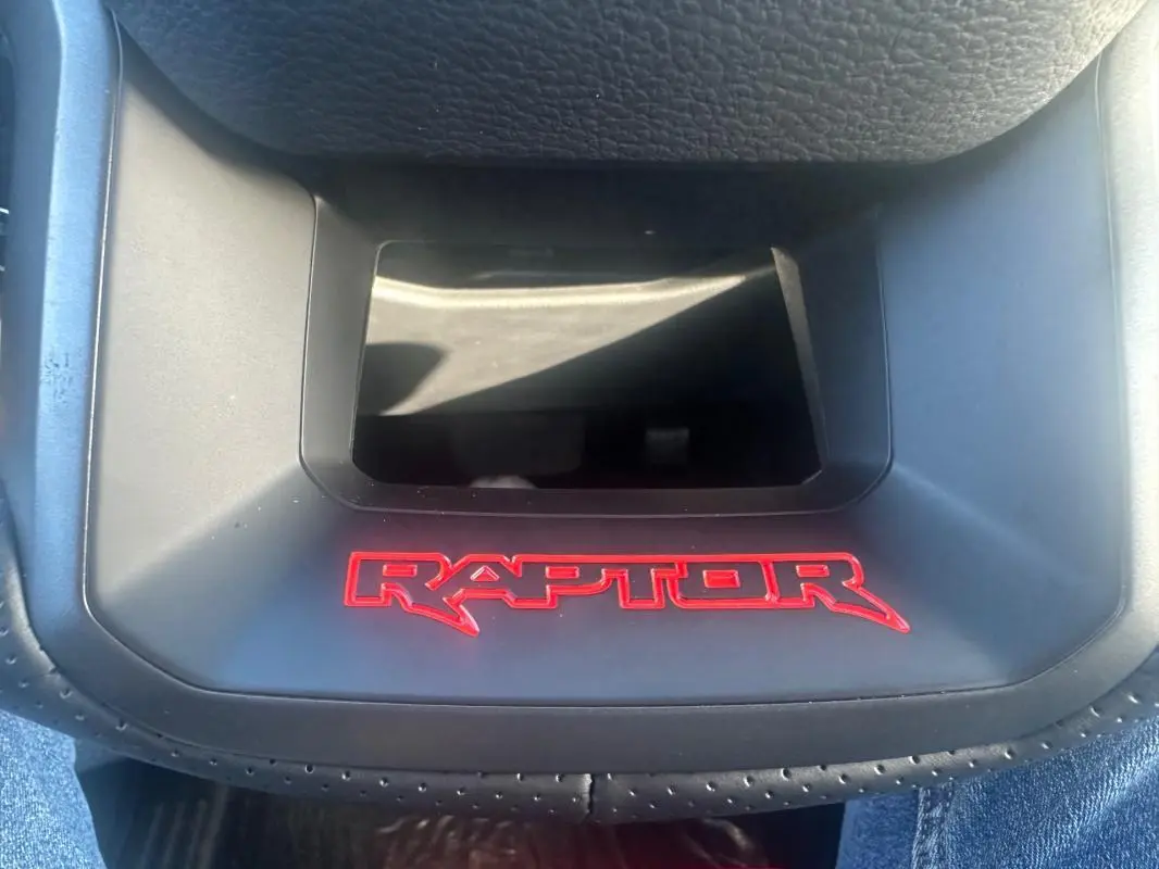 Gros plan sur le logo rouge RAPTOR sur la console centrale noire du Ford Ranger Raptor 2025, intérieur moderne.