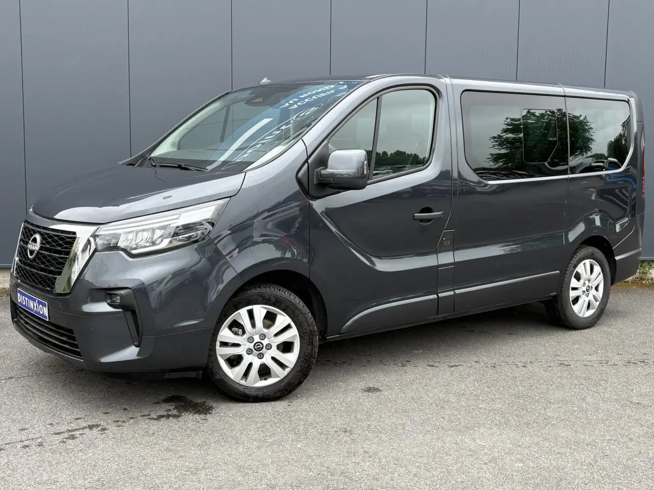 Vue 3/4 avant droit d’un Nissan Primastar gris comète avec hayon vitré et jantes alliage 17 pouces.