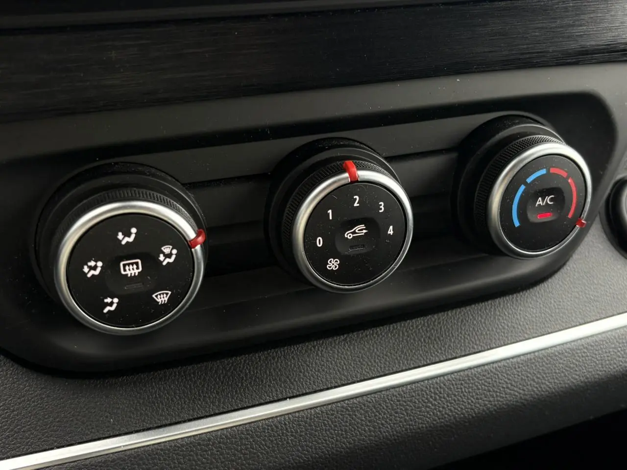 Gros plan sur les commandes de climatisation du Nissan Primastar gris Comète, boutons ronds avec réglages ventilation et A/C.