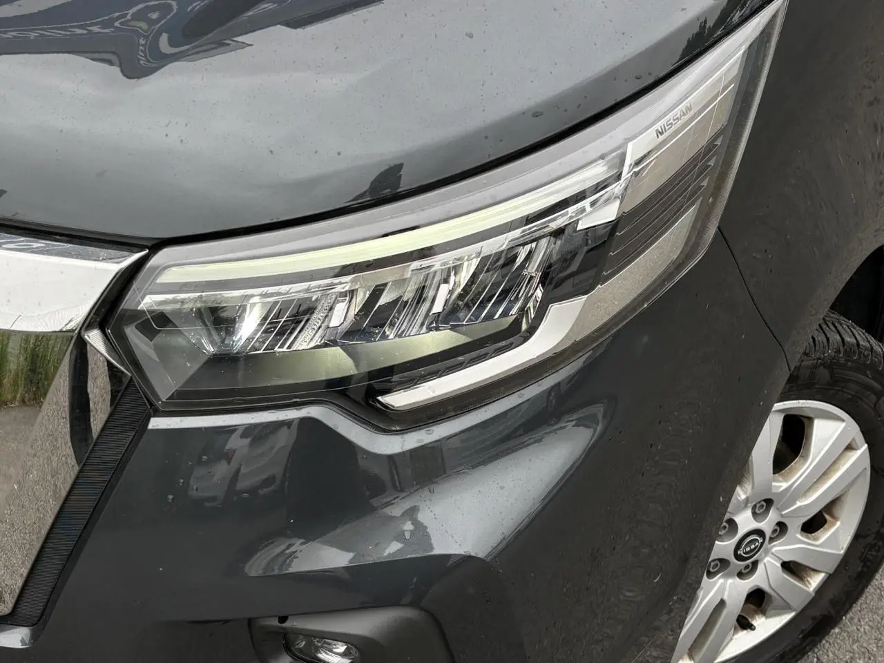 Gros plan sur le phare avant droit gris comète du Nissan Primastar 2025 avec jante alliage visible.