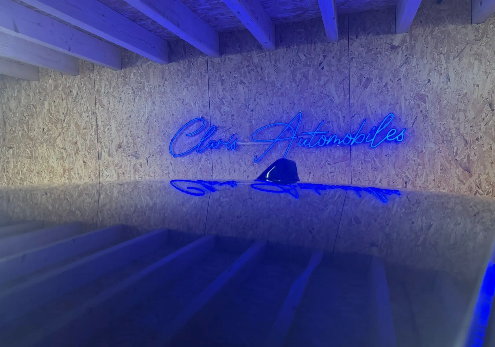 Je ne vois pas de véhicule sur cette image, seulement un mur en bois avec un néon bleu indiquant "Claris Automobiles".