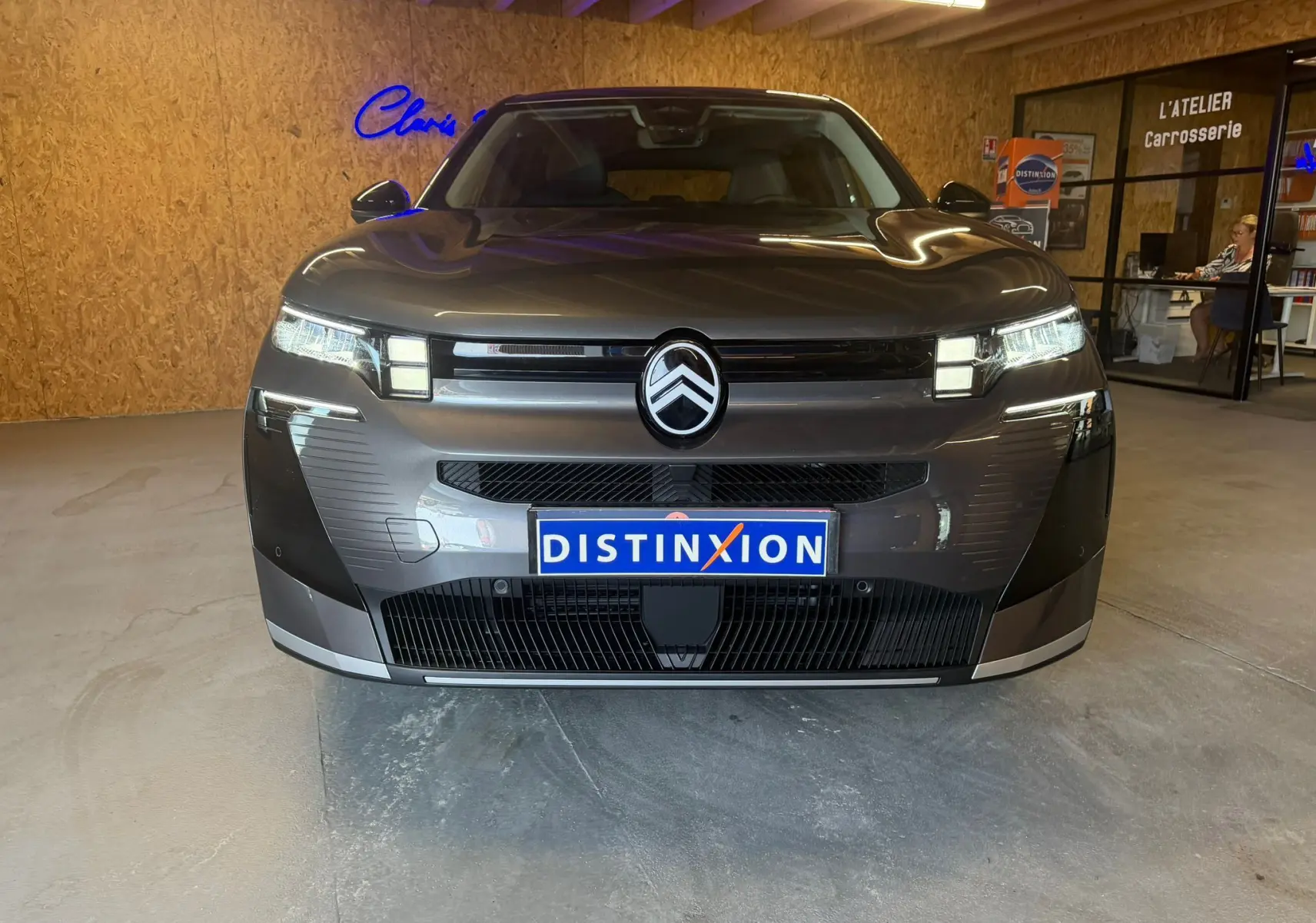 Vue frontale d'un Citroën C5 Aircross gris 2026 avec calandre noire et logo Citroën proéminent, en intérieur showroom.