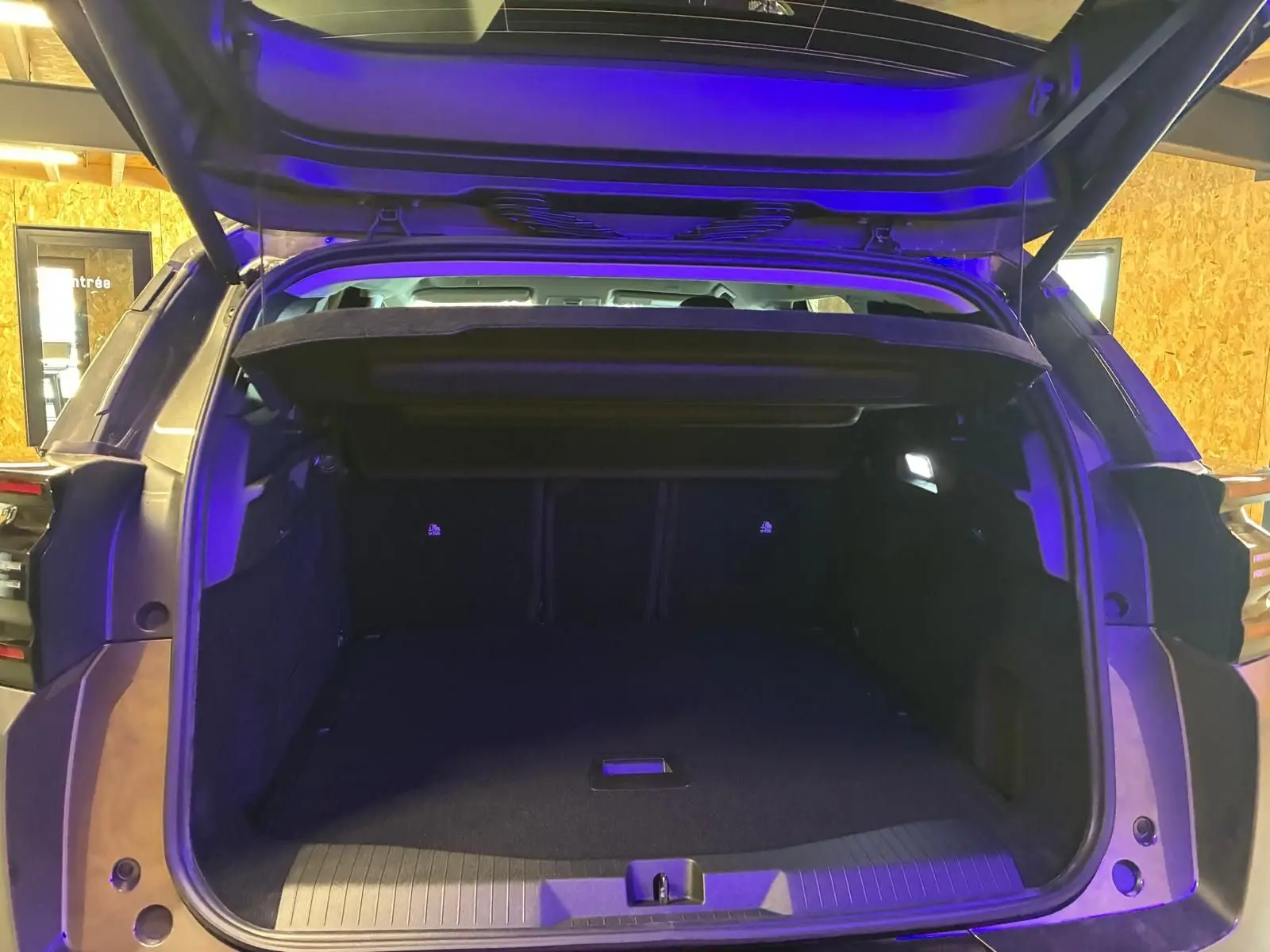 Coffre ouvert vu de l'arrière d'un Citroën C5 Aircross gris, intérieur spacieux avec éclairage LED bleu.