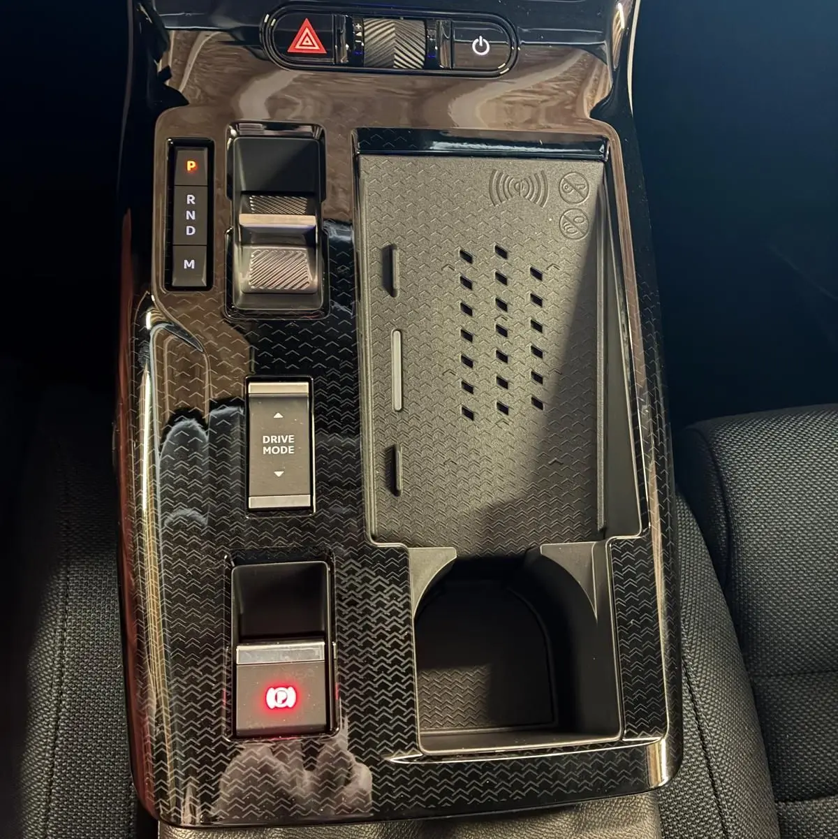 Vue rapprochée de la console centrale noire brillante du Citroën C5 Aircross 1.2 Hybride 145 Plus avec commandes de boîte auto et chargeur sans fil.