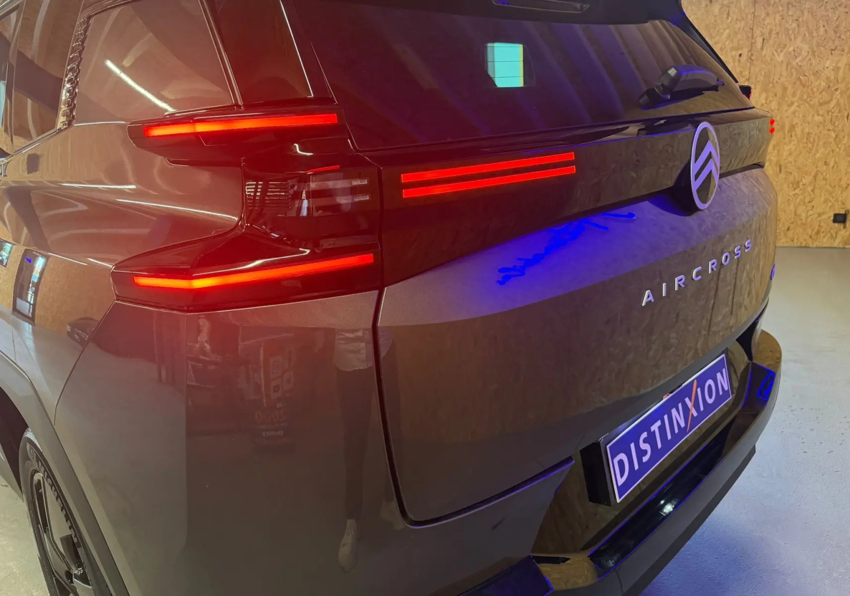 Vue 3/4 arrière droite du Citroën C5 Aircross gris 2026 avec feux arrière LED allumés et logo distinctif au centre.