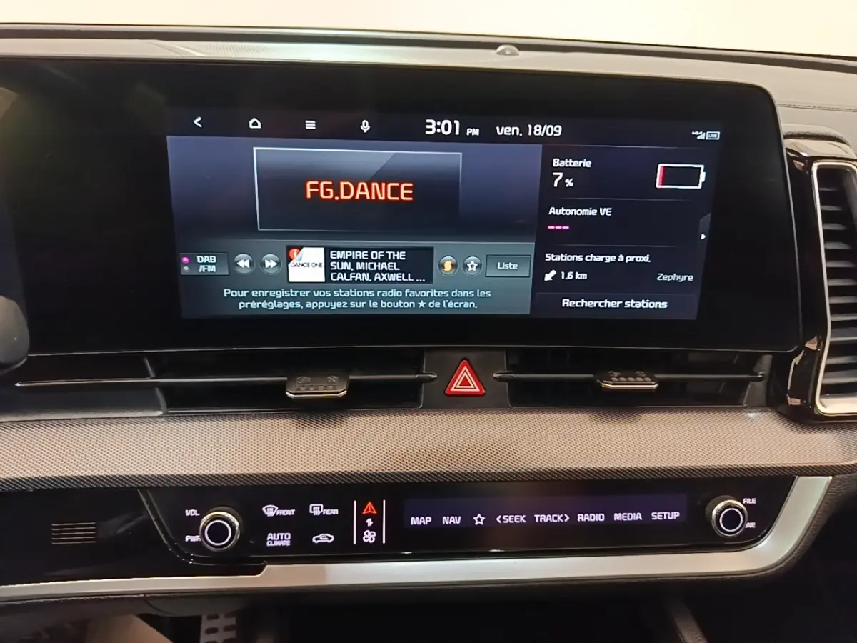 Tableau de bord du Kia Sportage 2022 avec écran tactile 12,3 pouces affichant radio et informations batterie.