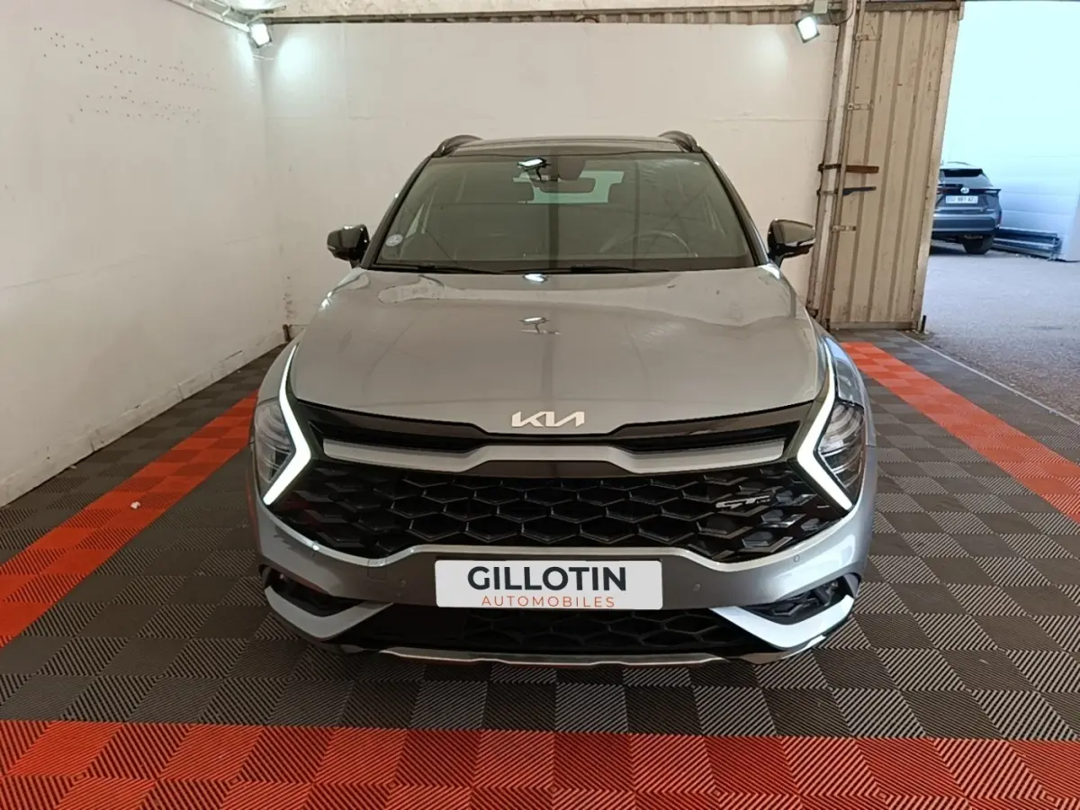 Vue avant d'un KIA Sportage gris clair avec phares LED en forme de C et calandre noire hexagonale.