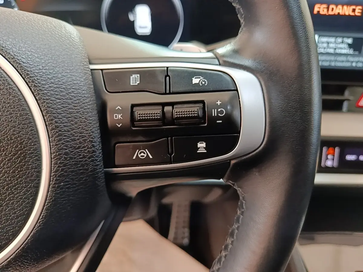 Gros plan sur les commandes de régulateur de vitesse au volant cuir noir du Kia Sportage hybride rechargeable 2022.