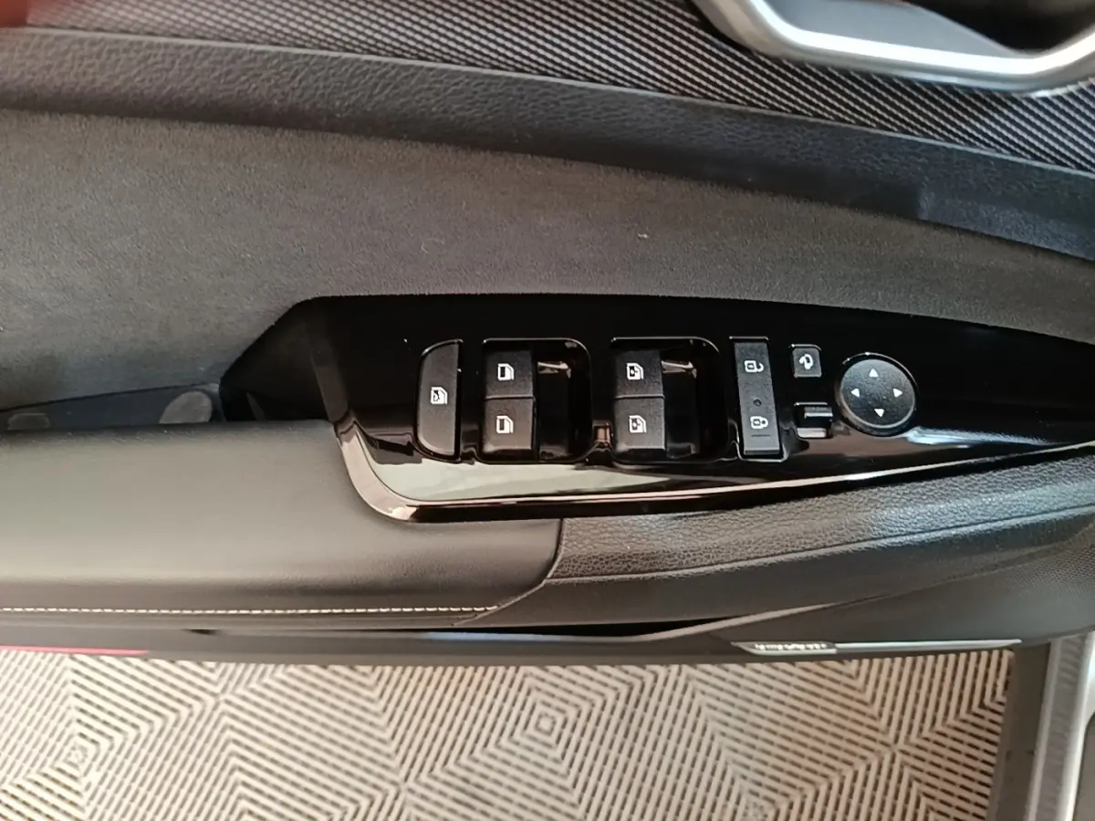 Vue rapprochée du panneau de commandes des vitres côté gauche en plastique noir brillant sur porte intérieure grise du Kia Sportage 2022.
