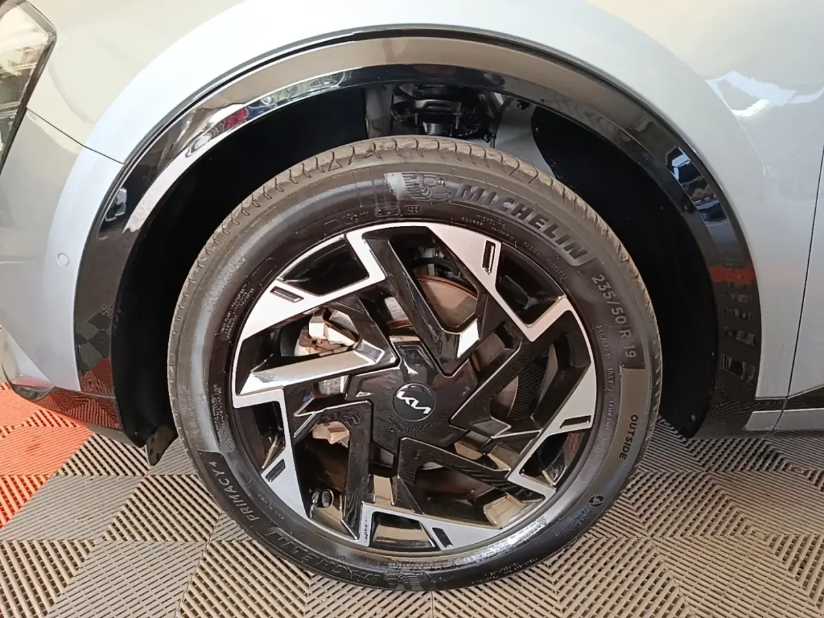 Gros plan sur la roue avant droite du KIA Sportage gris clair, jante alliage noire et argentée au design moderne.