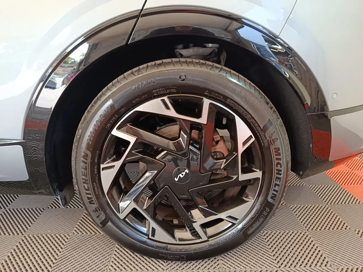 Gros plan sur la roue avant droite gris clair du KIA SPORTAGE 2022 avec jante noire et argentée au design géométrique.