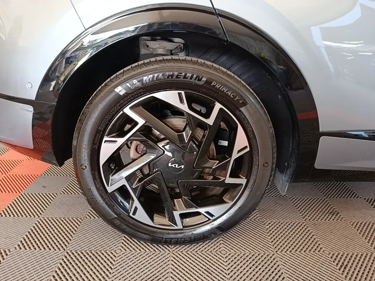 Gros plan sur la roue avant droite du Kia Sportage gris clair 2022 avec jante noire et argentée au design moderne.