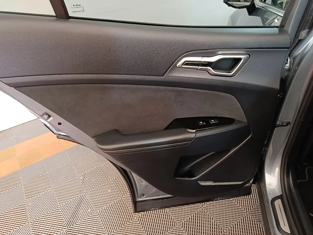Vue intérieure de la porte arrière droite gris clair du KIA SPORTAGE 2022 avec garniture noire et commandes de fenêtre.