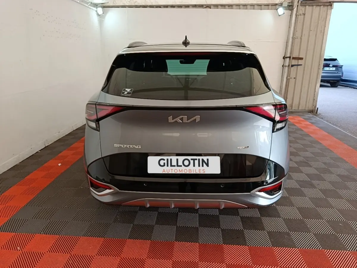Vue arrière d'un KIA Sportage gris clair 2022 avec logo et feux LED distinctifs dans un garage.