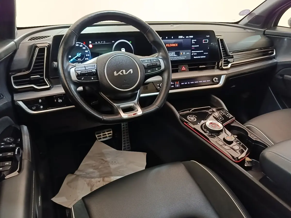 Vue intérieure du poste de conduite du Kia Sportage gris clair 2022, avec volant cuir multifonctions et écran tactile large.