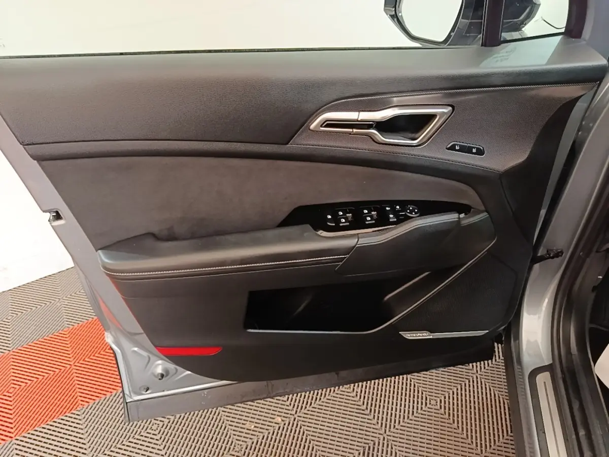 Vue intérieure côté gauche de la porte avant gris clair du Kia Sportage avec commandes électriques et insert noir.
