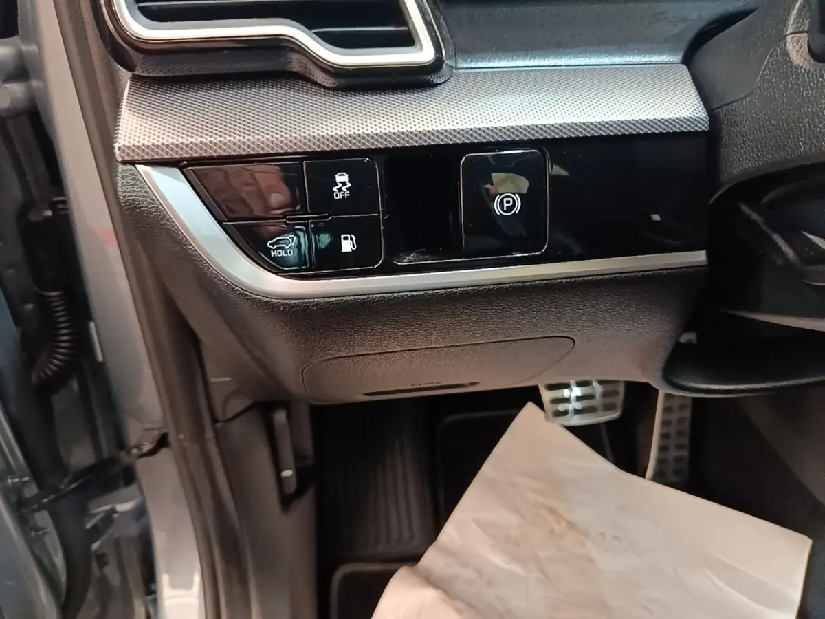 Détail intérieur côté gauche avec commandes électroniques et finition noire brillante du Kia Sportage gris clair 2022.