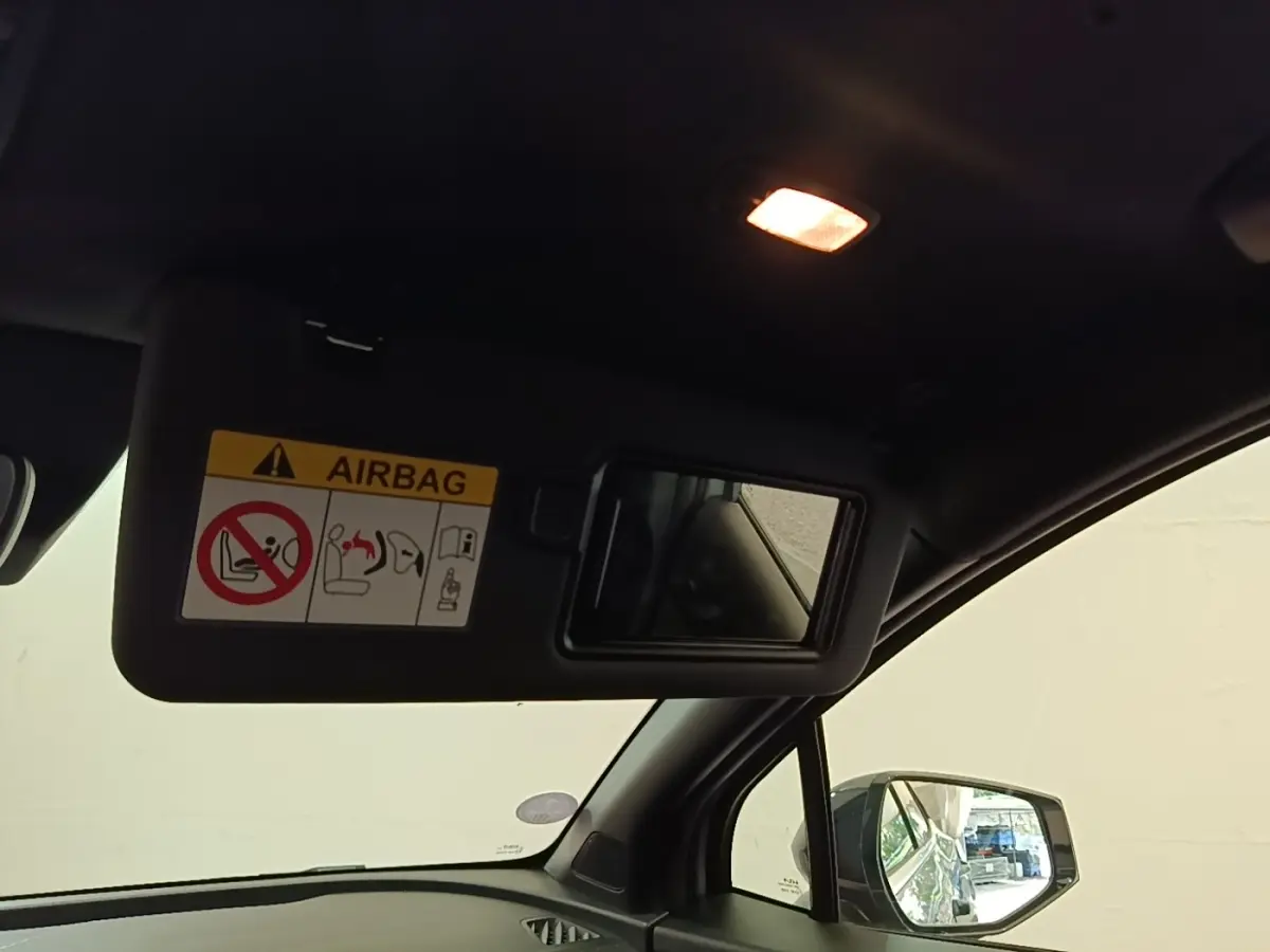 Vue intérieure côté conducteur du Kia Sportage 2022, miroir pare-soleil ouvert avec avertissement airbag visible.