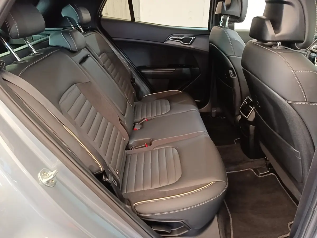 Vue intérieure côté gauche des sièges arrière en cuir noir du Kia Sportage gris clair, avec surpiqûres contrastantes visibles.